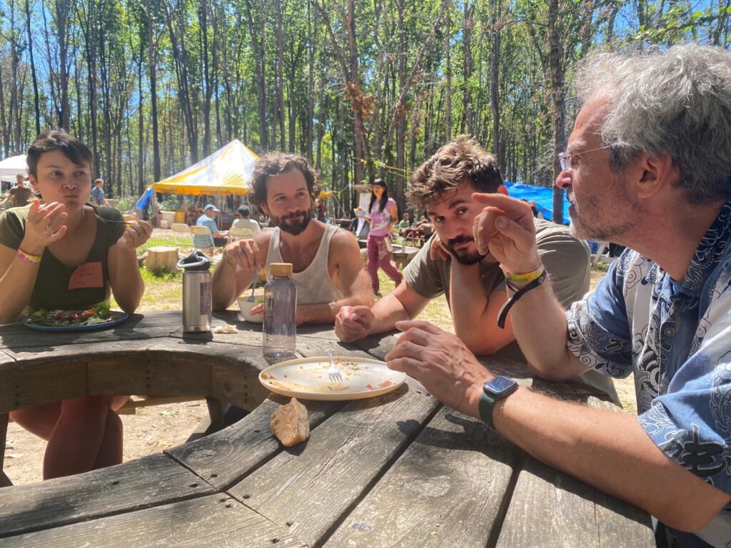 Bianca, Cristo, Dave, and Daniel from the FIC eating at a table at the Twin Oaks Conference